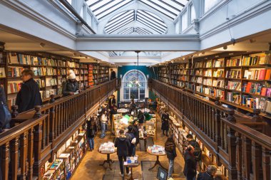Daunt Kitabevinin içinde ahşap raflar, tavan penceresi ve kitap okuyan müşteriler var. Londra, İngiltere, 25 Şubat 2024