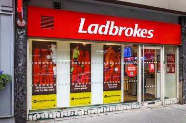 Ladbroke 'lar vitrinlerinde kırmızı pankartlar ve tanıtım posterleriyle harici bahis oynuyorlar. Londra, İngiltere, 25 Şubat 2024