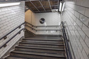 Londra metro istasyonu merdiven boşluğunun temiz fayanslı duvarları ve endüstriyel tasarımı olan iç çekimi..