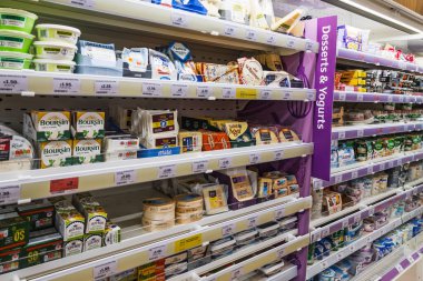 Market rafları geniş peynir ürünleri ve alışveriş yapanlar için çeşitli tatlılarla dolu. Londra, İngiltere, 3 Mart 2024