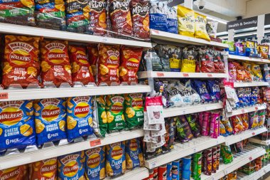 Süpermarket rafları abur cubur severler için çeşitli cips ve cipslerle dolu. Londra, İngiltere, 3 Mart 2024