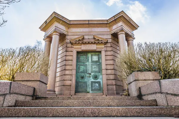 Büyük taş sütunları ve yeşil kapıları olan tarihi Highgate Mezarlığı girişi, önemli bir Londra simgesi. Londra, İngiltere, 3 Mart 2024