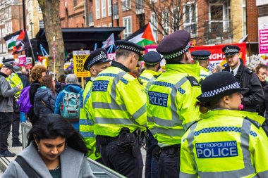 Parlak ceketli polis memurları halka açık bir sokak gösterisinde düzeni ve kalabalığı kontrol ediyorlar. Londra, İngiltere, 16 Mart 2024