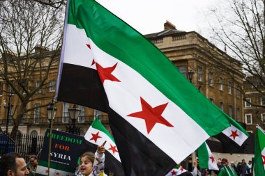 Suriye 'nin özgürlük ve demokrasisini savunan bir halk gösterisi sırasında Suriye için Özgürlük bayrağını sallayan aktivistler. Londra, İngiltere, 16 Mart 2024