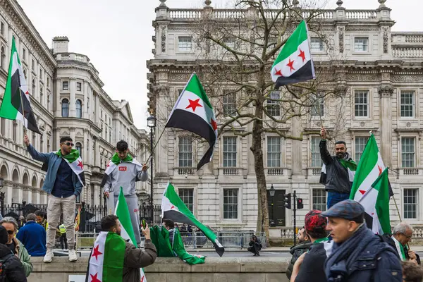 Suriye 'nin bağımsızlık bayrağını elinde tutan bir grup aktivist, siyasi reform için düzenlenen halk gösterisinde bayrak sallıyor. Londra, İngiltere, 16 Mart 2024