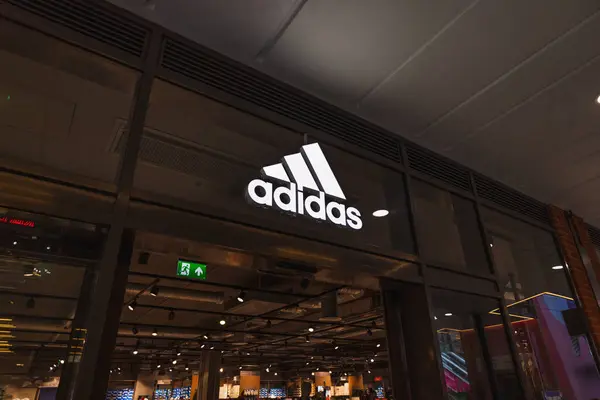 Adidas mağazasının dış cephesinde, alışveriş merkezinde parlak logo ve cam vitrinler var. Londra, İngiltere, 17 Mart 2024