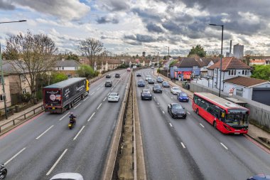 Bulutların altında kamyonlar ve yolcu vagonları da dahil olmak üzere yoğun trafikle dolu çok şeritli bir otoyol. Londra, İngiltere, 17 Mart 2024