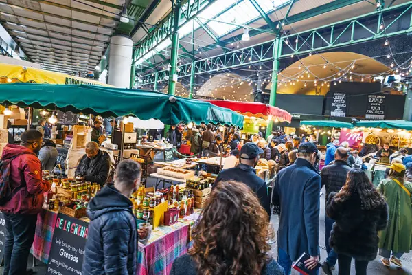 Telaşlı Borough Market, taze gıda tezgahları ve canlı piyasa yaşamının tadını çıkaran müşterilerle dolu. Londra, İngiltere, 29 Mart 2024