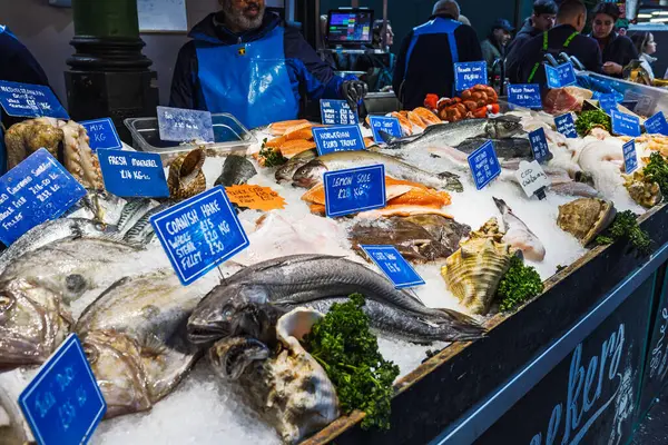Meşgul Borough Market deniz ürünleri standında buzda sergilenen taze balık ve kabuklu deniz ürünleri. Londra, İngiltere, 29 Mart 2024