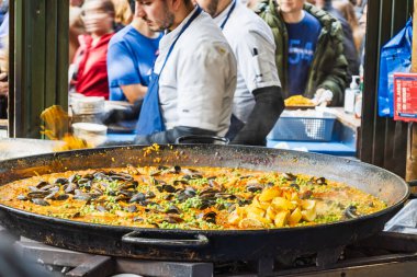 Geleneksel İspanyol paella taze hazırlandı ve kalabalık ile canlı gıda pazarında servis edildi..