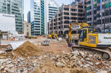 Etrafı binalar ve toprak yığınlarıyla çevrili bir inşaat alanında çalışan kazıcı. Londra, İngiltere, 29 Mart 2024