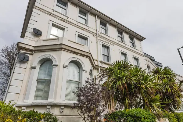 Önünde kendine özgü mimarisi ve tropikal bitkileri olan klasik Viktorya dönemi çok katlı evi..