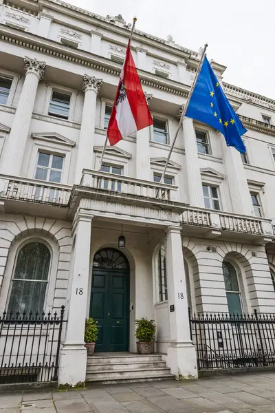 Avusturya Büyükelçiliği Londra 'nın dış tarafında klasik mimari sergileniyor ve ulusal bayraklar dalgalanıyor. Londra, İngiltere, 6 Nisan 2024
