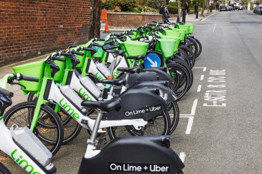 Yeşil şehir hareketliliğini desteklemek için kaldırım boyunca sıralanmış elektrikli kireç mobiletleri. Londra, İngiltere, 7 Nisan 2024