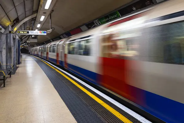 Londra metro istasyonunda hızla giden bir metro treninin dinamik hareket bulanıklığı. Şehir ulaşımı, ulaşım ve şehir içi taşıma konsepti. Londra, İngiltere, 6 Nisan 2024