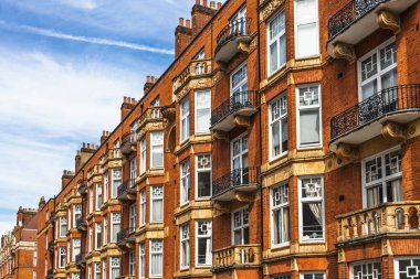 Londra 'da süslü balkonları ve mavi gökyüzü olan geleneksel kırmızı tuğlalı Edwardian daireleri.