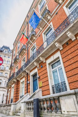 Tarihi bir kırmızı tuğla bina üzerinde ulusal ve AB bayraklarıyla Londra 'daki Portekiz Konsolosluğu. Londra, İngiltere, 14 Nisan 2024