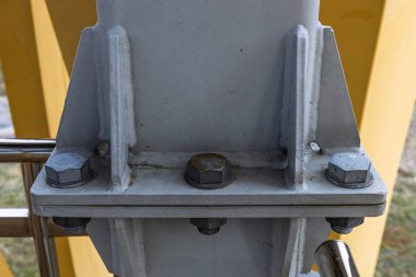 Endüstriyel mühendislik, inşaat veya yapısal bütünlük görselleri için ideal gri çelik bir sütunu güvence altına alan kaynaklı kaplama ve ağır cıvataların makro görünümü.