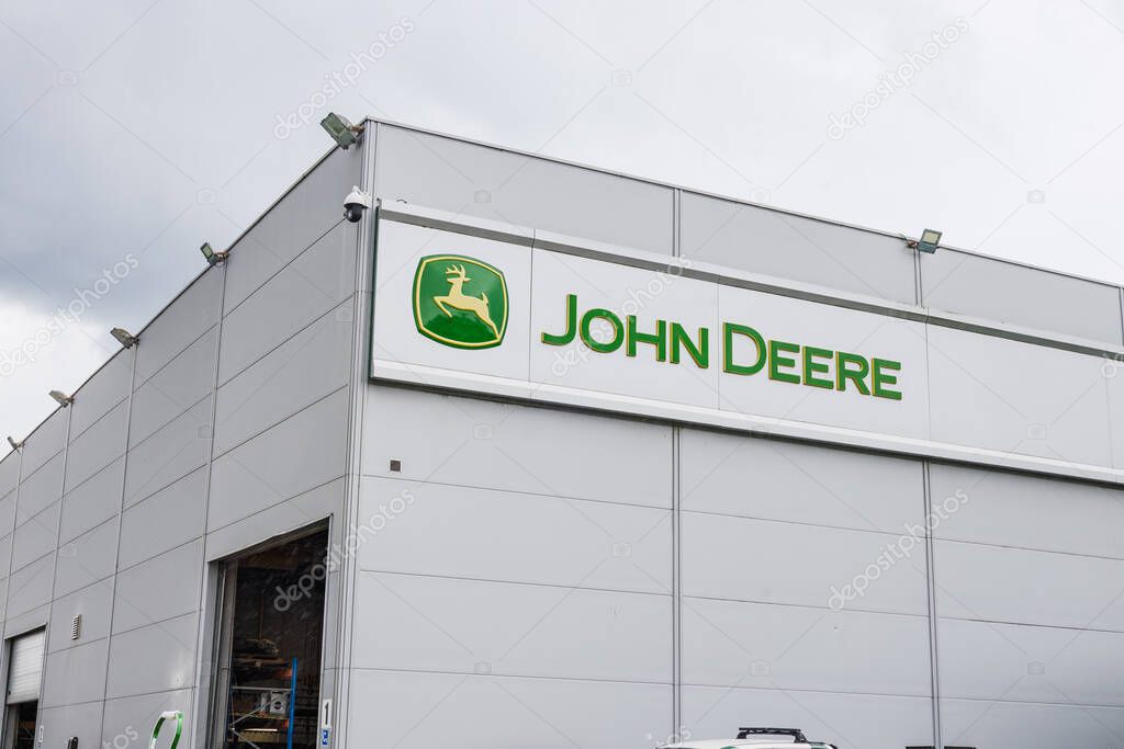 John Deere dealership exterior featuring the green logo on a modern industrial building facade. Kaunas, Lithuania, 19 June 2025