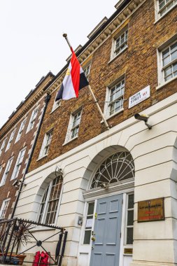 Londra, Westminster 'daki Arap Cumhuriyeti Büyükelçiliği. Kahverengi tuğla Gürcistan cephesi, kemerli kapı, plaket ve bulutlu kış gökyüzüne karşı ulusal bayrak. Londra, İngiltere, 14 Nisan 2024