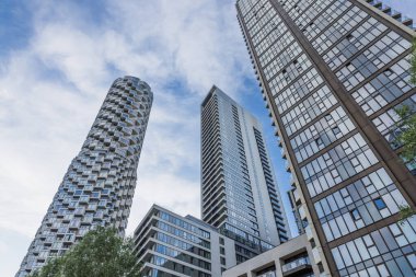 Parlak camdan gökdelenler, modern mimari, şehir yaşamı ve parlak mavi gökyüzünü gösteriyor..