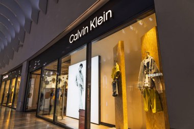 Calvin Klein lüks alışveriş merkezlerinde vitrin önü, aydınlatılmış logo, mankenler ve parlak cam cephe. Londra, İngiltere, 27 Mayıs 2024