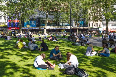 Londra 'nın merkezindeki Leicester Meydanı çimlerinde, popüler şehir parkında güneşli bir yaz öğle yemeği sırasında yerel halk ve turistler dinleniyor. Londra, İngiltere, 2 Haziran 2024