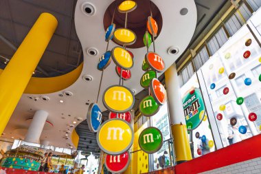 M ve M World 'ün iç mekanı. Tavan kocaman renkli şeker logoları diskleri, parlak ışıklar ve eğlenceli dekorlarla doluyken büyüleyici bir şekerleme alışveriş deneyimi yaratıyor. Londra, İngiltere, 2 Haziran 2024