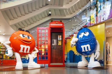 Büyük boy kırmızı ve mavi M ve M heykelleri Londra 'daki bayrak gemisinin şeker dükkanında bulunan klasik kırmızı telefon kulübesinde, perakende satış ve turizmi gösteriyor. Londra, İngiltere, 2 Haziran 2024
