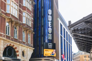 Odeon sinemasının dış görünüşü koyu mavi bir cephede koyu beyaz bir tabela ve tarihi tuğla bina zeminine karşı büyük bir dijital reklam panosu gösteriyor. Londra, İngiltere, 2 Haziran 2024