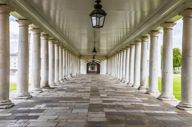 Greenwich, Londra 'daki Eski Kraliyet Donanma Koleji sütununun simetrik görüntüsü. Neoklasik sütunlar, taş kaldırımlar ve asılı fenerler..
