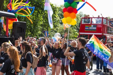 Gururlu kalabalık Londra 2024 'te gökkuşağı balonları, Progress Pride bayrağı ve kırmızı çift katlı otobüsle tezahürat yapıyor. Londra, İngiltere, 29 Haziran 2024