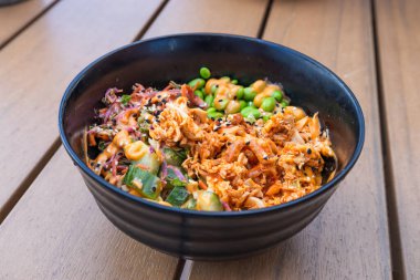 Üzeri soğanlı ve susamlı baharatlı pilavı tahtada siyah bir kaseye koy..