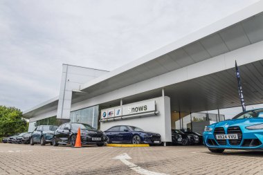 BMW bayisi dış yüzeyinde büyük beyaz gölgelikler, sergi salonu girişi, işaretli yerler ve ön avluda arabalar var. Portsmouth, İngiltere, 3 Temmuz 2024