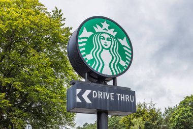Starbucks yeşil logo ve sol okla bir kahve dükkanı için açık hava perakende satış yolu bulma tabelasından geçiyor. Portsmouth, İngiltere, 3 Temmuz 2024