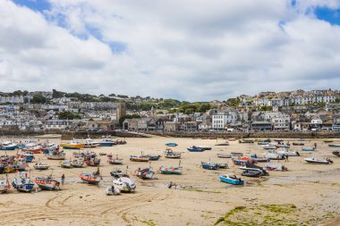 St. Ives, Cornwall 'da güneşli bir liman. Islak kumda ve kır evlerinin yamacında kayıklar var. St Ives, İngiltere, 4 Temmuz 2024