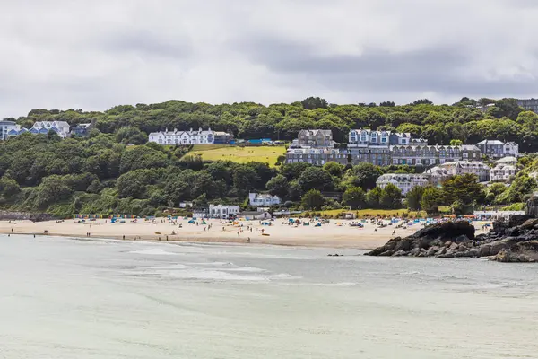 St. Ives, Cornwall yakınlarındaki Carbis Körfezi 'nin yüksek manzarası. Kumsal, turkuaz su, yamaçtaki oteller ve yumuşak bulutların altındaki yemyeşil ağaçlar. St Ives, İngiltere, 4 Temmuz 2024