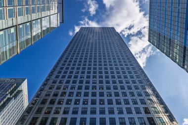 Bir Kanada Meydanı 'nın ve Canary Wharf, Londons finans bölgesinin çevresindeki cam kulelerin dramatik alçak açılı görüntüsü, dağınık bulutlu, mavi bir gökyüzünün altında. Londra, İngiltere, 19 Mayıs 2023