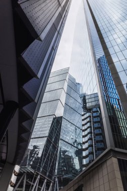 Şehir mimarisinin özünü yansıtan cam yansımalı modern gökdelenlerin alçak açılı görüntüsü.