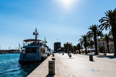 TROGIR, CROATIA - 30 Ekim 2022: Yatı, Kamerlengo sarayı ve eski Trugir kasabasında palmiye ağaçları olan gezinme alanı.