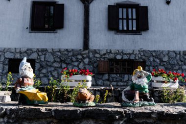 Bahçe cüceleri ve çiçek arkaplanı ve duvarı olan bir kurbağa..