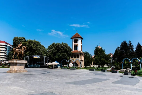 TARGOVISTE, ROMANIA - JULY 29, 2022: The old bell tower of  the Ascension Metropolitan cathedral and Michael the Brave statue in the Metropolitan park.
