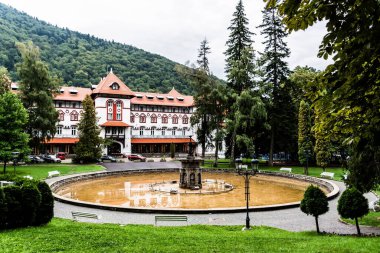 Dimitrie Ghica parkındaki artezya çeşmesi ve arkasında da Caraiman Oteli. Sinaia, Romanya.