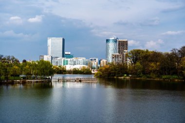 BUCHAREST, ROMANIA - Nisan 09, 2023: Bordei parkındaki Floreasca Gölü 'ndeki Pontoon ve Aurel Vlaicu bölgesindeki ofis binaları.