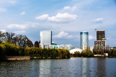 BUCHAREST, ROMANIA - Nisan 09, 2023: Bordei parkındaki Floreasca Gölü 'ndeki Pontoon ve Aurel Vlaicu bölgesindeki ofis binaları.