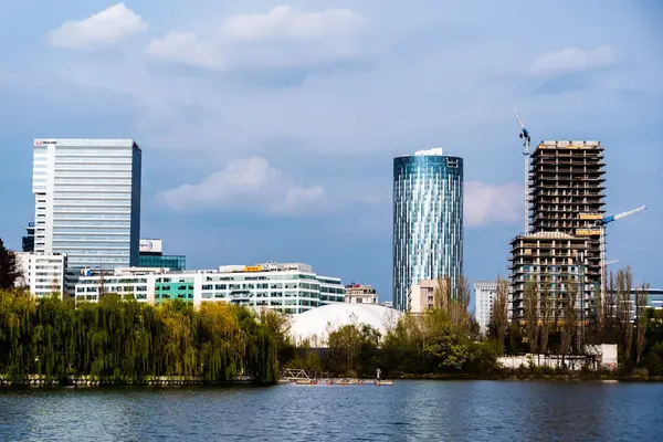 BUCHAREST, ROMANIA - Nisan 09, 2023: Bordei parkındaki Floreasca Gölü 'ndeki Pontoon ve Aurel Vlaicu bölgesindeki ofis binaları.