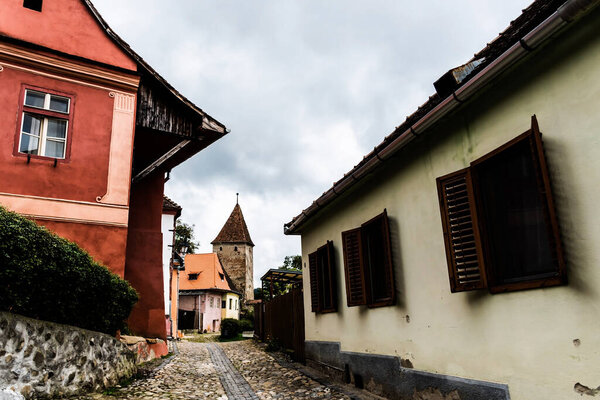 Old medieval street with colorful houses and in the background is the Furriers tower. Sighisoara, Romania.