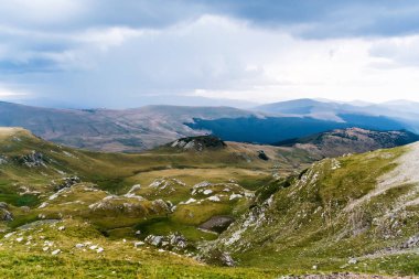 Dağlar, yeşil tepeler ve bulutlu gökyüzü, Transalpina yolu, Romanya.