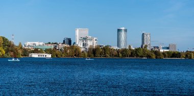 BUCHAREST, ROMANIA - 28 Ekim 2023: Herastrau Parkı bir sonbahar günü, gölde tekneler ve arka planda ofis binaları.