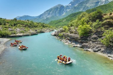 A group of four yellow rafts floating among the rocks on the crystal clear, blue-green water of Vjosa river, Albania. clipart